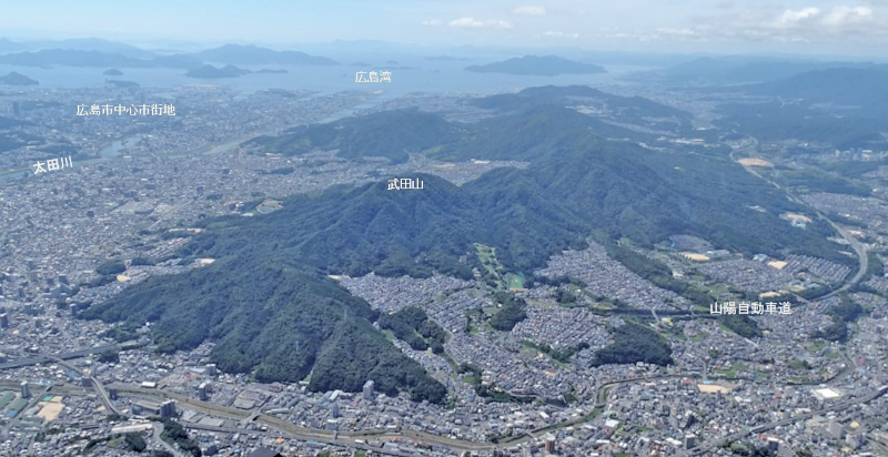 【写真－1　広島市の山裾まで住宅地が開発されている状況（空撮）】